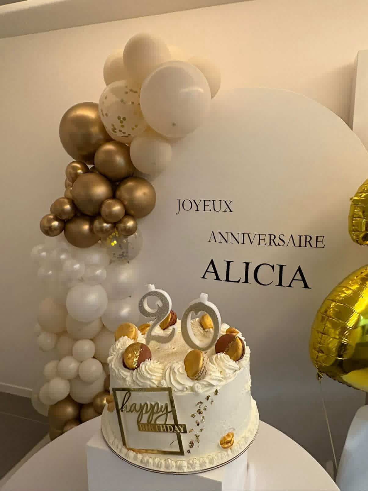 Décoration anniversaire dorée avec arche de ballons et gâteau