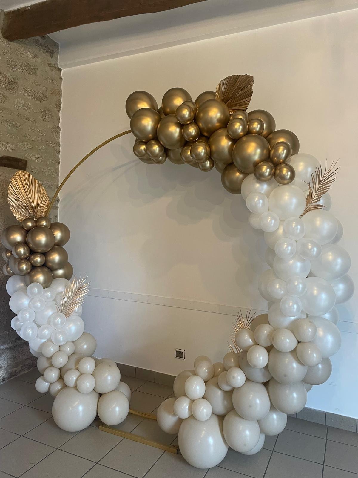 Arche ronde de ballons blanc et or avec feuilles de palmier