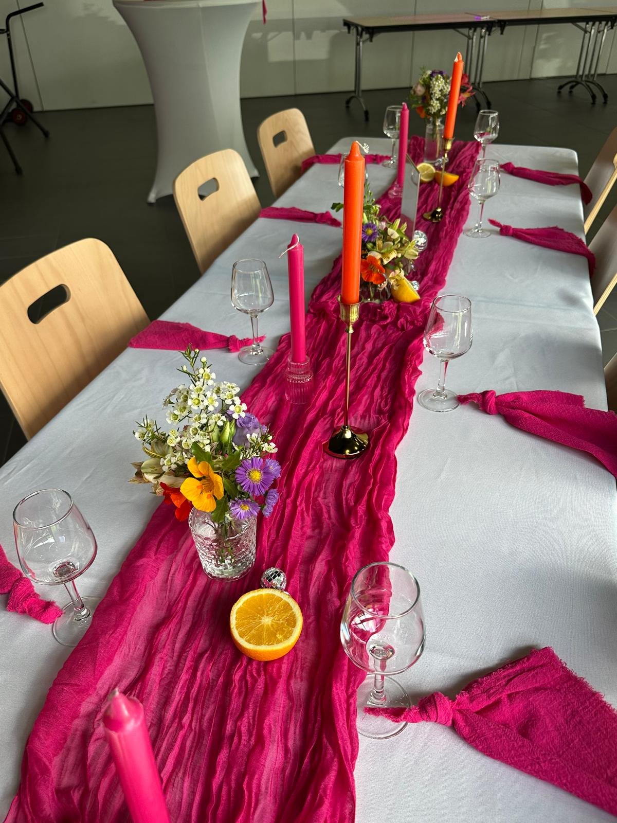 Table décorée avec chemin de table fuchsia et bougies orange