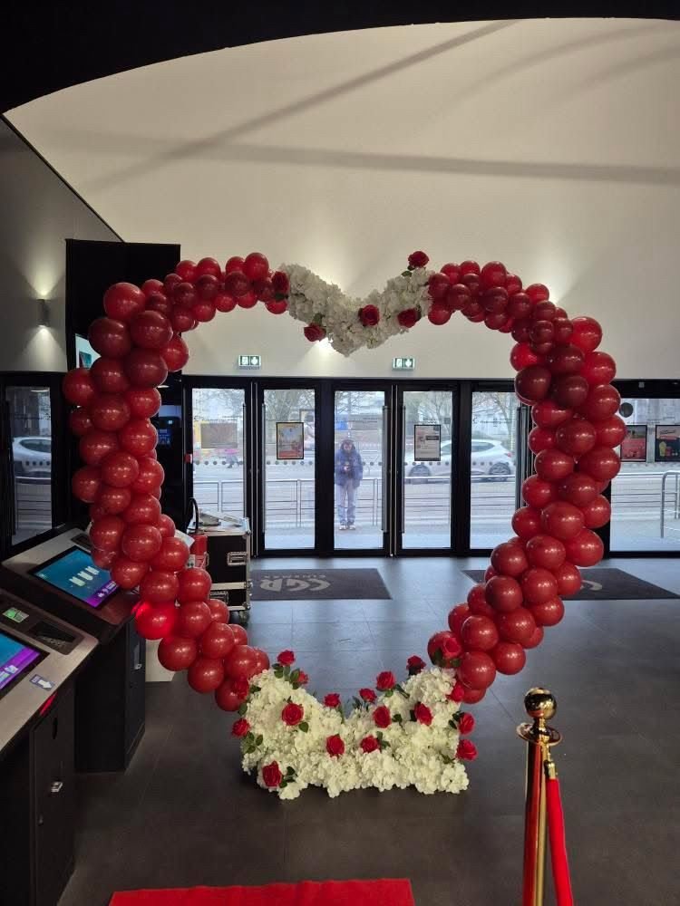 Arche cœur de ballons rouges avec fleurs blanches, tapis rouge